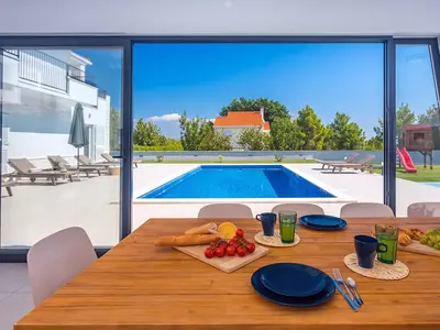 Eine voll ausgestattete Sommerküche mit TV, Kühlschrank, Grill und Essbereich für 10 Personen