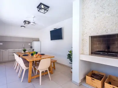 Eine voll ausgestattete Sommerküche mit TV, Kühlschrank, Grill und Essbereich für 10 Personen