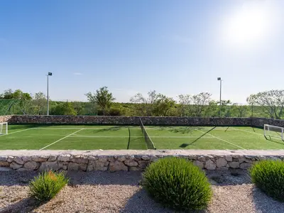 Ein eingezäunter Tennisplatz mit Kunstrasen und 4 Schlägern, kann auf Wunsch auch als Fußballplatz genutzt werden