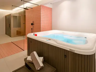 Ein Wellnessraum mit finnischer Sauna, Whirlpool im Innenbereich, Dusche und Toilette