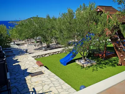 Ein kurzer Spaziergang vom Poolbereich führt zur Spielzone für Kinder, die eine Rutsche und mehrere Leseecken zwischen Olivenbäumen bietet.