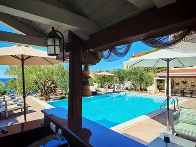 Von der Poolbar und dem Terrassenbereich aus genießen Gäste den Blick auf den Pool und das Meer, während sie kühle Getränke genießen.