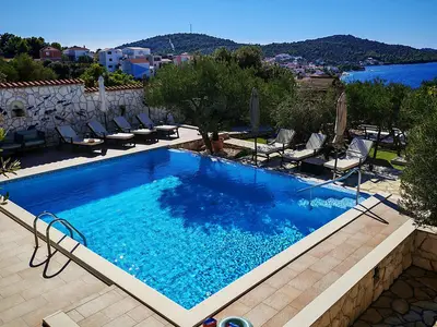 Der private Swimmingpool mit seinem hellblauen Wasser und der umliegenden Sonnenterrasse ist das Herzstück des Außenbereichs und bietet Meerblick.