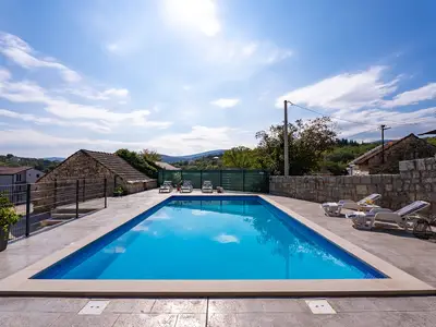 Die weitläufige Sonnenterrasse umgibt den glitzernden, 50 m2 großen privaten Swimmingpool und bietet einen idealen Ort zum Entspannen und Sonnenbaden.