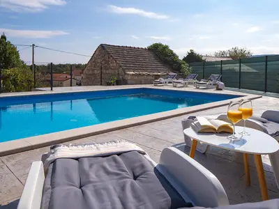 Der einladende Poolbereich bietet bequeme Sitzgelegenheiten und Sonnenliegen, ideal, um in einem Buch zu schmökern oder bei einem erfrischenden Getränk die Sonne zu genießen.