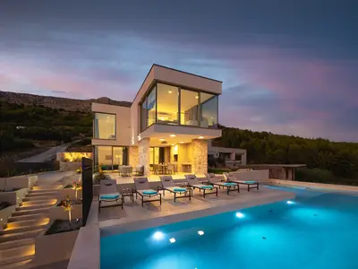 Abendaufnahme der zweistöckigen Villa mit Poolbereich, die Teil des 203 m2 großen, mondänen Wohnraums ist.