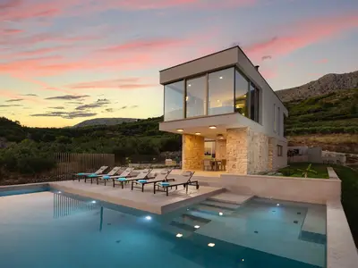 Die exklusive Villa verfügt über einen beheizten Pool und ein atemberaubendes Design vor der Kulisse der Berge bei Sonnenuntergang.