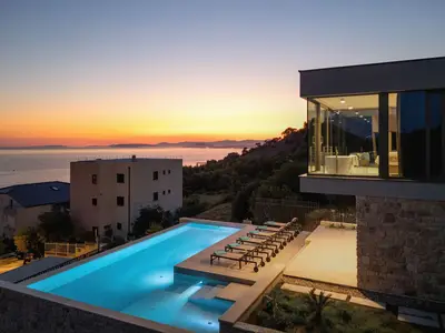 Blick auf den Pool und das luxuriöse Schlafzimmer 1 im Obergeschoss 30 m2 , das über eine freistehende Badewanne verfügt, die durch die Glaswand sichtbar ist.