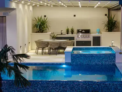 Der überdachte Essbereich im Freien ist mit einem Gasgrill ausgestattet und liegt neben dem integrierten Hydromassagebereich des Pools.