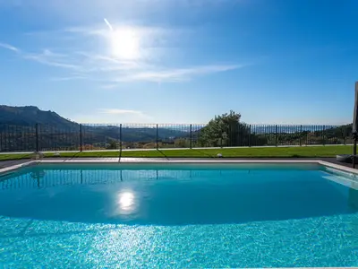 Der türkise 32 qm Pool und die grüne Rasenfläche, sicher eingezäunt und mit Blick auf die beeindruckenden Berge.