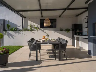 Überdachter Essbereich im Freien (Al Fresco Dining) in der voll ausgestatteten Sommerküche mit Fernseher und traditionellem Grill.