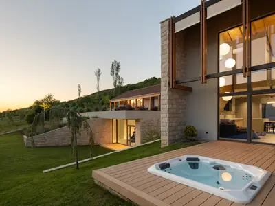 Modernes Design trifft auf traditionellen Stein, mit einem eleganten Außenwhirlpool und weitem Terrassenblick.