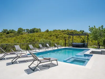 Sonnendeck mit Liegen, überdachter Whirlpool und freier Blick auf die umliegende Natur.
