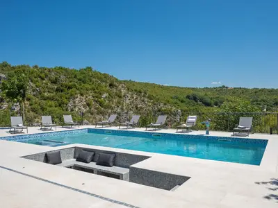 Großer beheizter Pool mit einzigartigem versunkenem Sitzbereich und Mosaikfliesen.