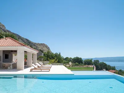 Genießen Sie den überdachten Essbereich mit Grill, TV und Lounge-Ecke für Mahlzeiten im Freien.