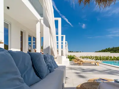 Lounge-Ecke vor dem Wohnzimmer, eine Sommerküche mit TV, Grill, Esstisch für 8 Personen und eine Toilette.