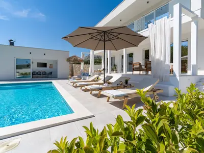 Lounge-Ecke vor dem Wohnzimmer, eine Sommerküche mit TV, Grill, Esstisch für 8 Personen und eine Toilette.