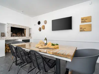 Eine Sommerküche mit TV, Grill, Esstisch für 8 Personen und Toilette