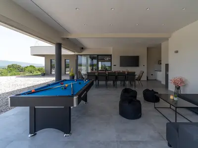 Überdachter Bereich (77 m2) mit einer Außenküche, einem traditionellen Grill (Holz und Holzkohle), einem riesigen Flachbildfernseher mit Surround-Lautsprechern und einem Esstisch für 12 Personen